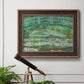 Impressionist garden scene with Japanese bridge and water lilies by Claude Monet in an ornate bronzed mahogany wood frame displayed in a light-toned interior setting.