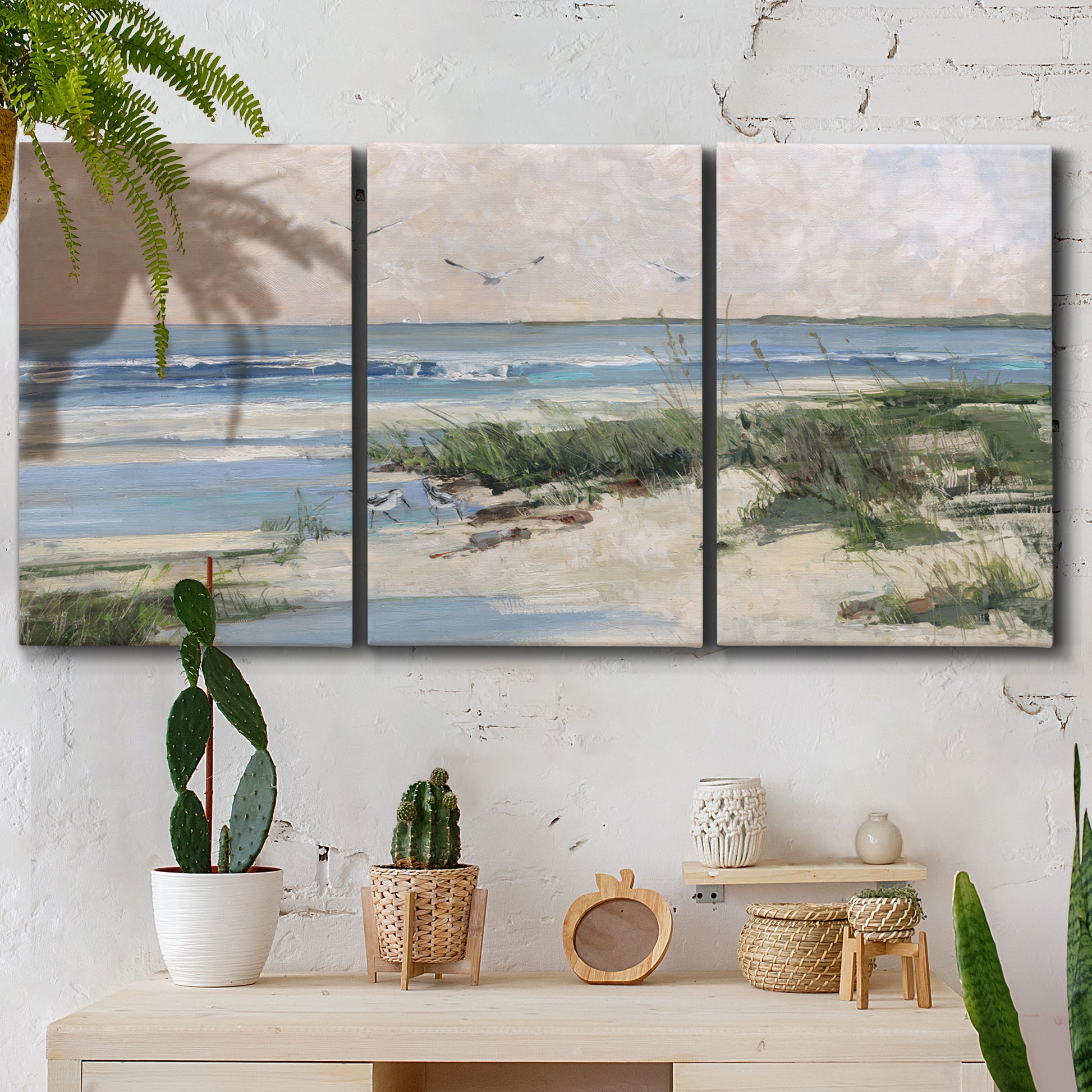 Three-panel canvas wall art featuring soft morning light over calm sea, displayed in a boho-chic entryway above a console table.