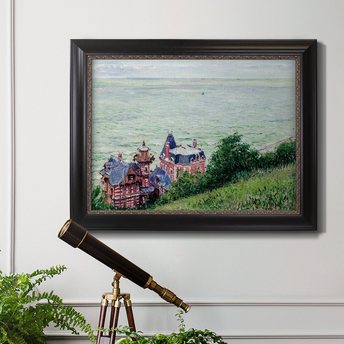 Impressionist coastal villas landscape by Gustave Caillebotte in an ornate black frame with gilded inner detail displayed in a light-toned interior setting.