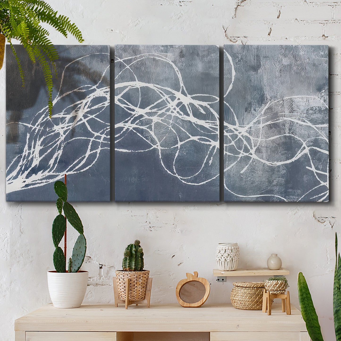 Three-panel canvas wall art featuring coastal shoreline at golden hour, displayed in a boho-chic entryway above a console table.