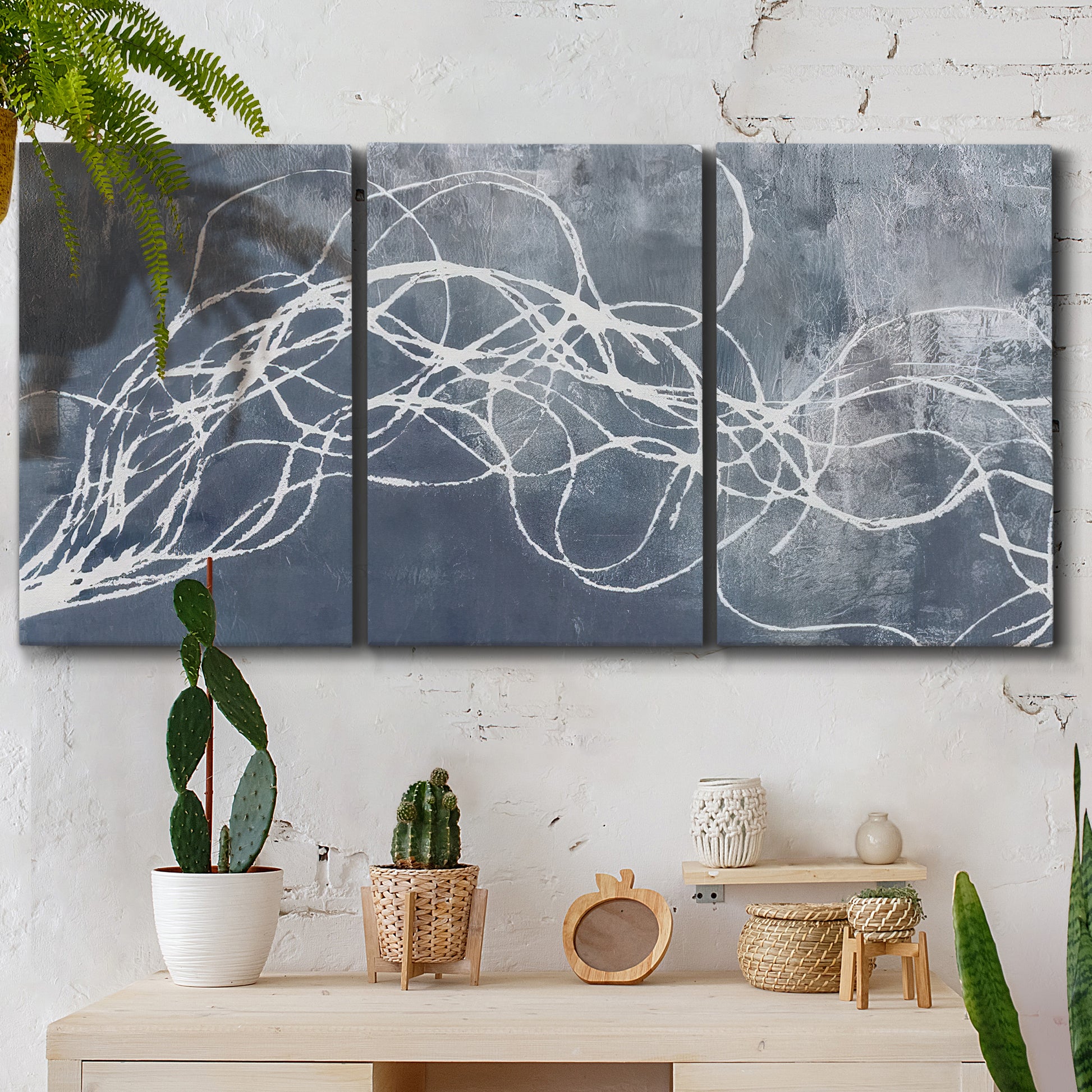 Three-panel canvas wall art featuring coastal shoreline at golden hour, displayed in a boho-chic entryway above a console table.
