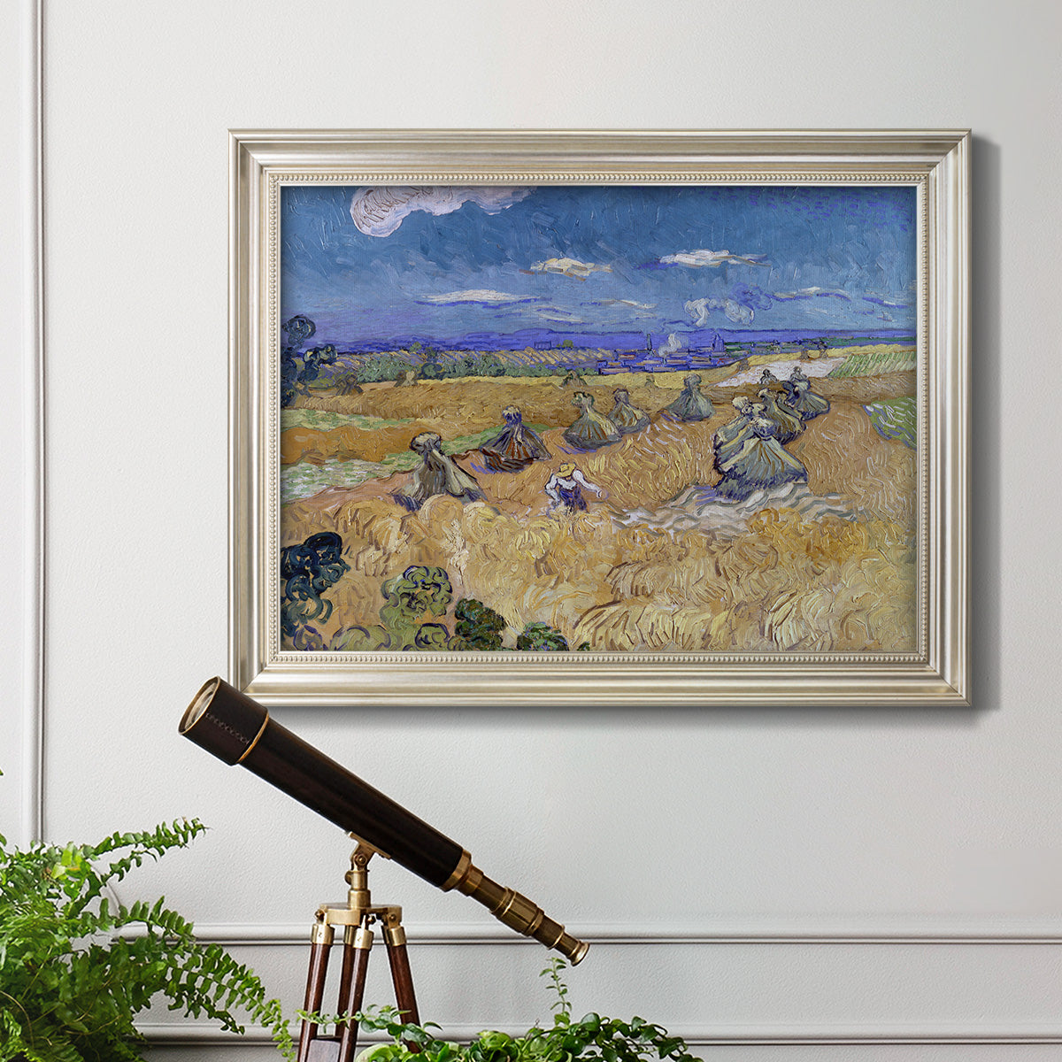 Impressionist wheat harvest scene by Vincent van Gogh in an ornate champagne frame displayed in a light-toned interior setting.