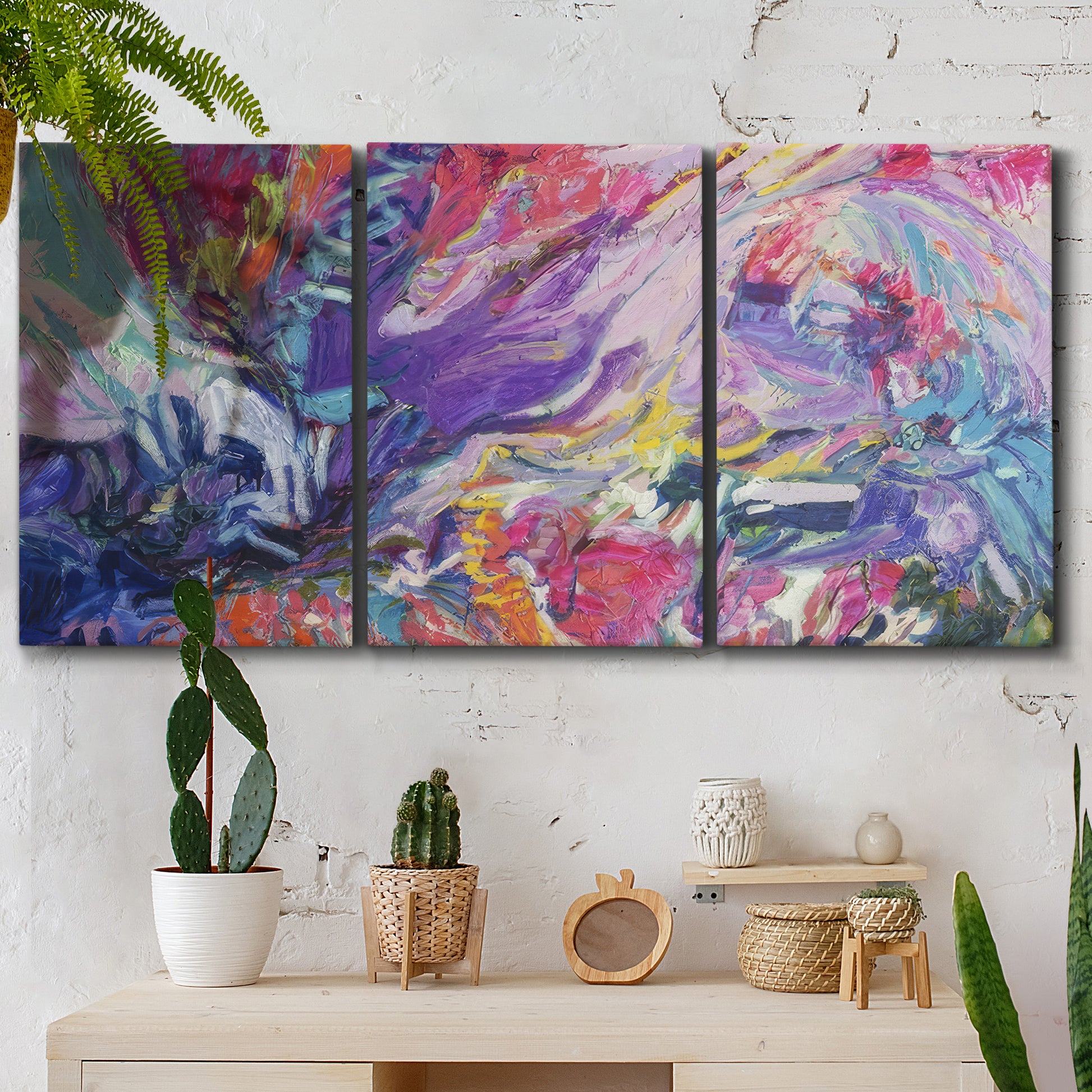Three-panel canvas wall art featuring expressive abstract with layered color, displayed in a boho-chic entryway above a console table.