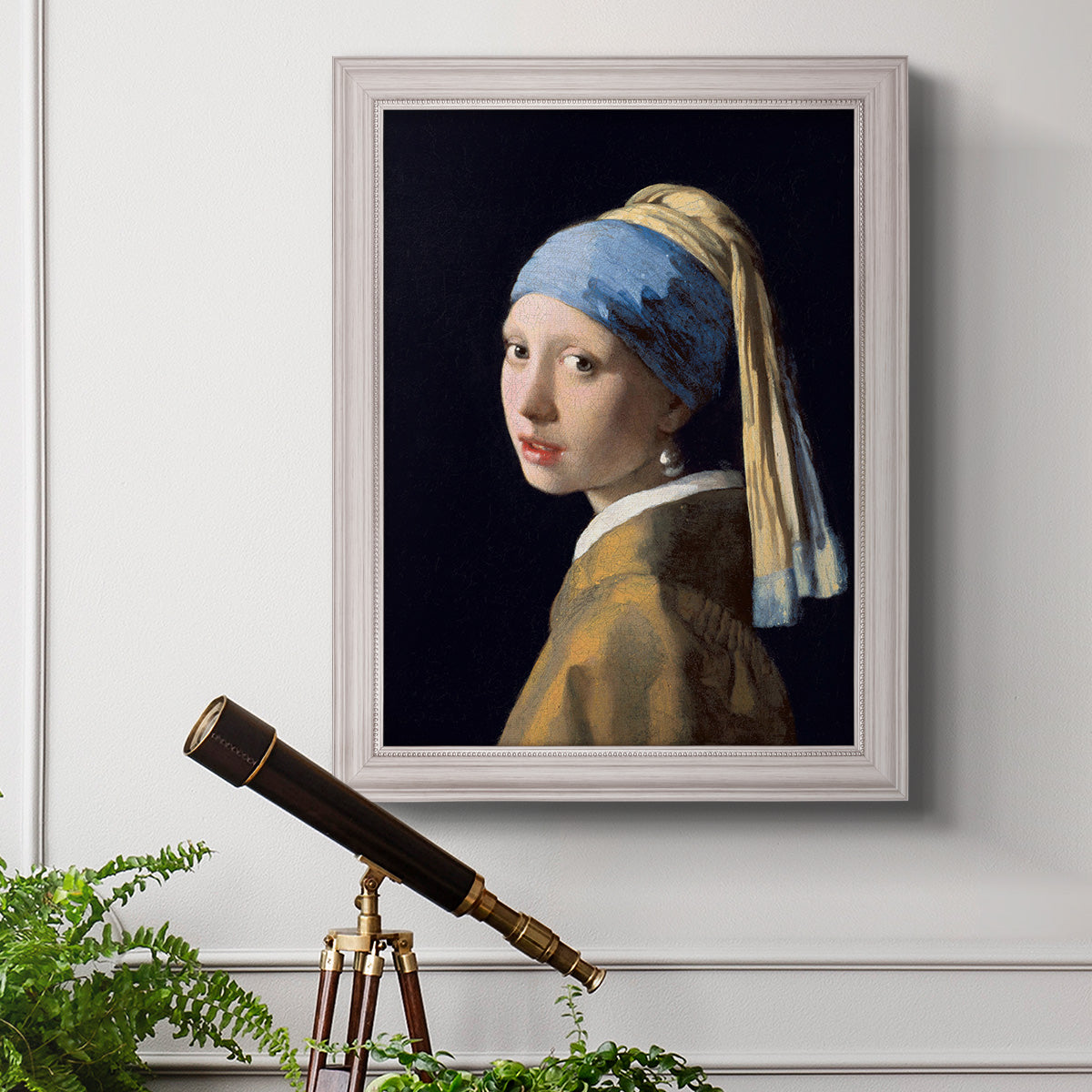 Iconic portrait of a girl wearing a pearl earring by Johannes Vermeer in an ornate weathered white frame displayed in a light-toned interior setting.