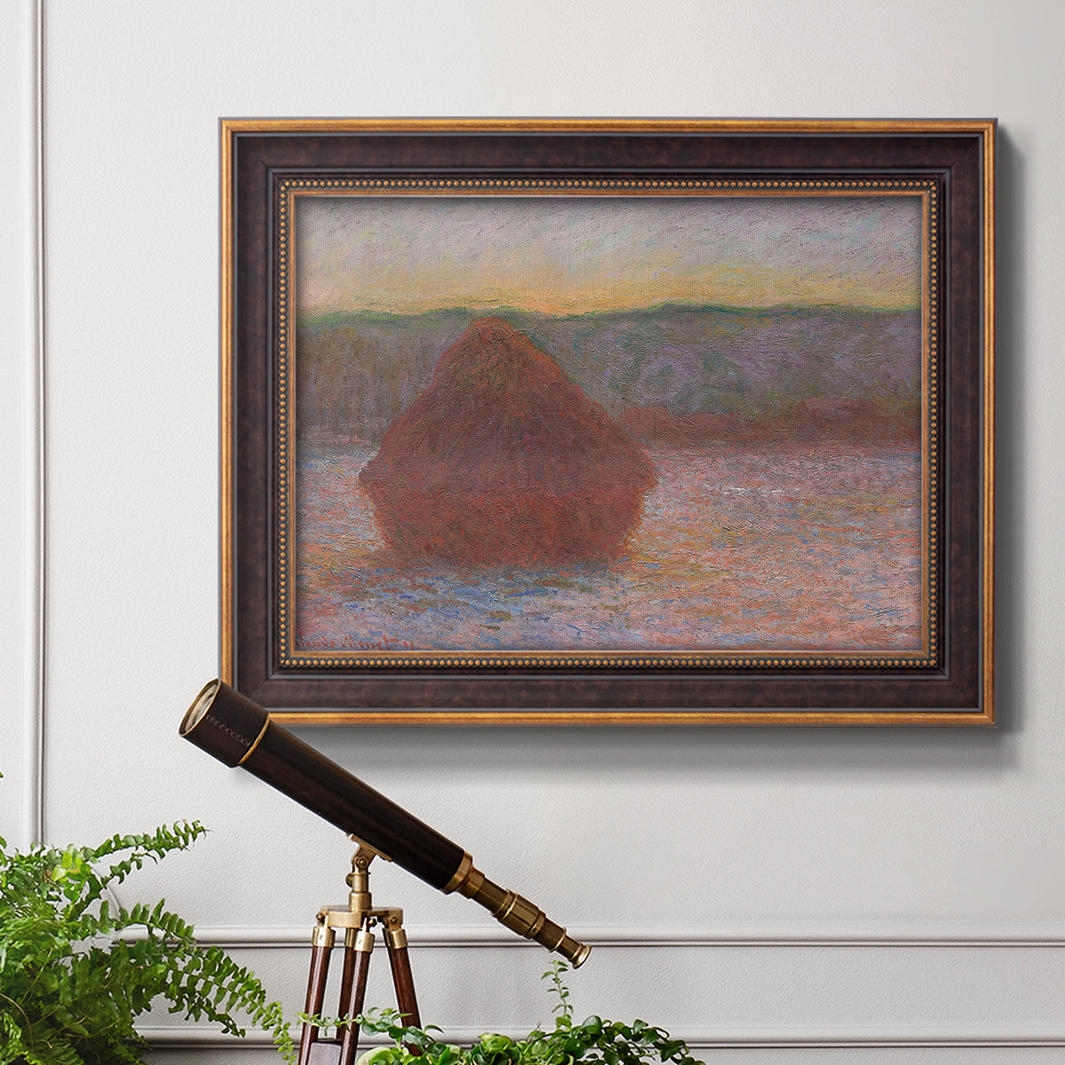 Impressionist haystack sunset scene in winter by Claude Monet in an ornate bronzed mahogany wood frame displayed in a light-toned interior setting.