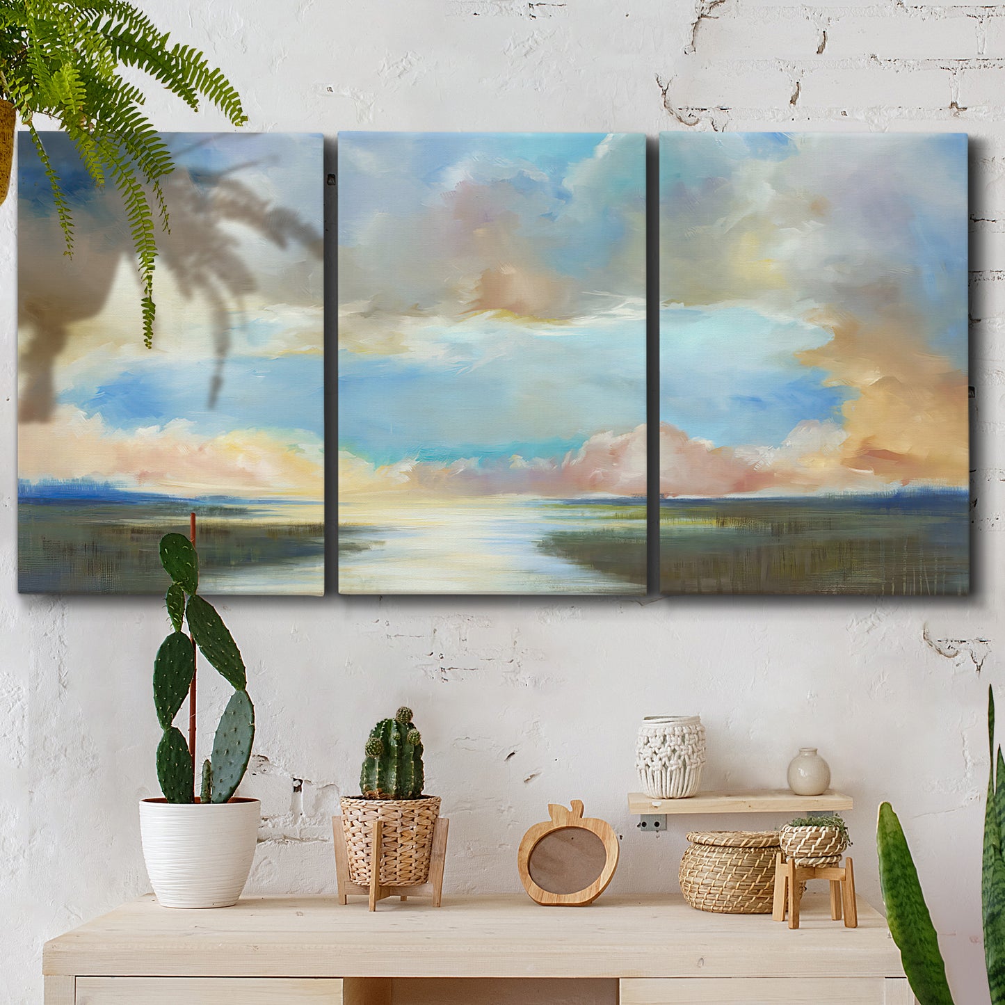 Three-panel canvas wall art featuring dawn light breaking over water, displayed in a boho-chic entryway above a console table.