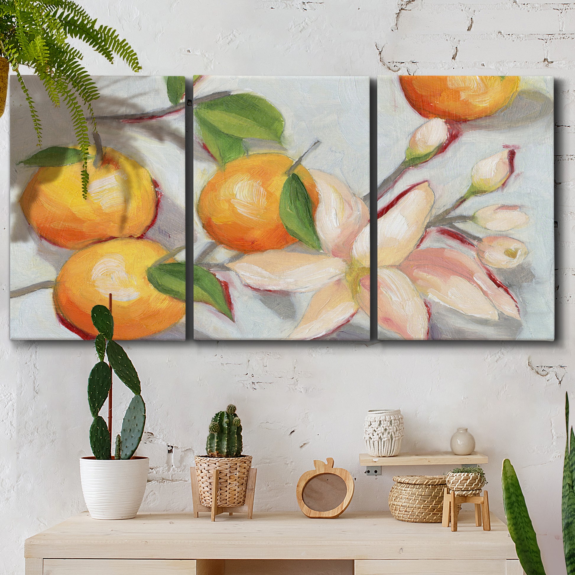 Three-panel canvas wall art featuring bright tangerine still life blossoms, displayed in a boho-chic entryway above a console table.