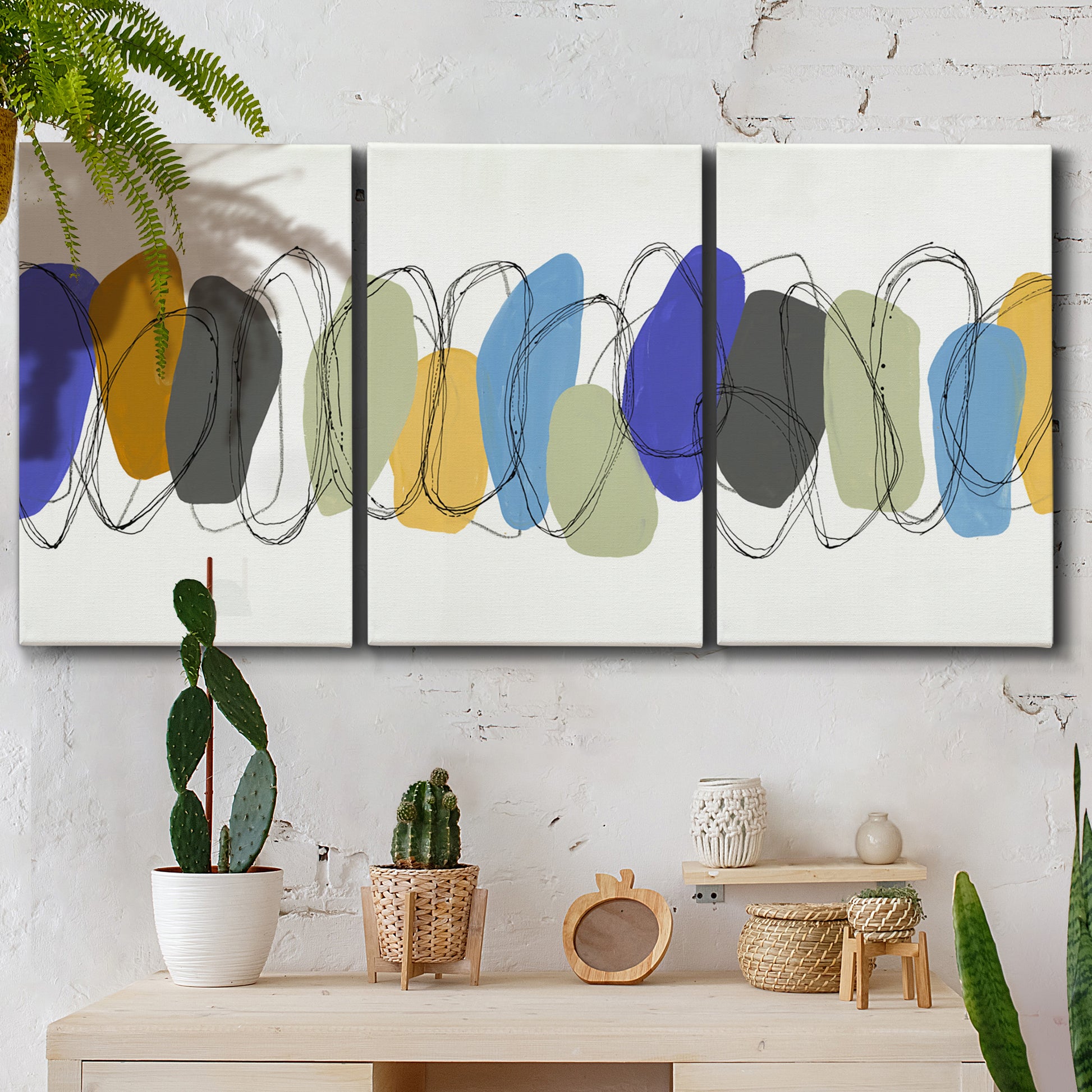 Three-panel canvas wall art featuring minimalist geometric abstract spacing, displayed in a boho-chic entryway above a console table.