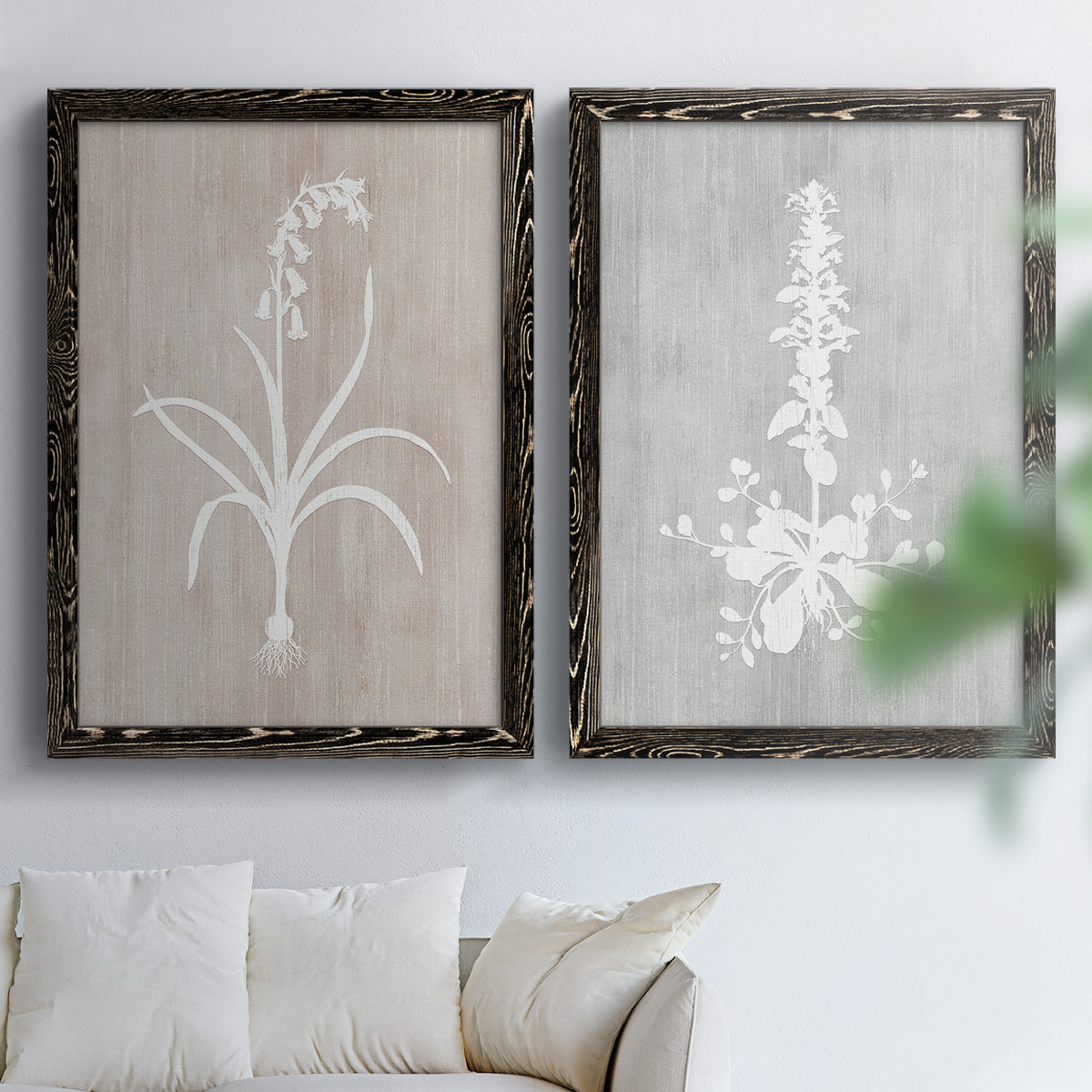Set of two black barnwood framed canvas prints depicting delicate stems, leaves, and blossoms against gray taupe and pale blue panels arranged across two complementary compositions above a sofa in a bright living space.