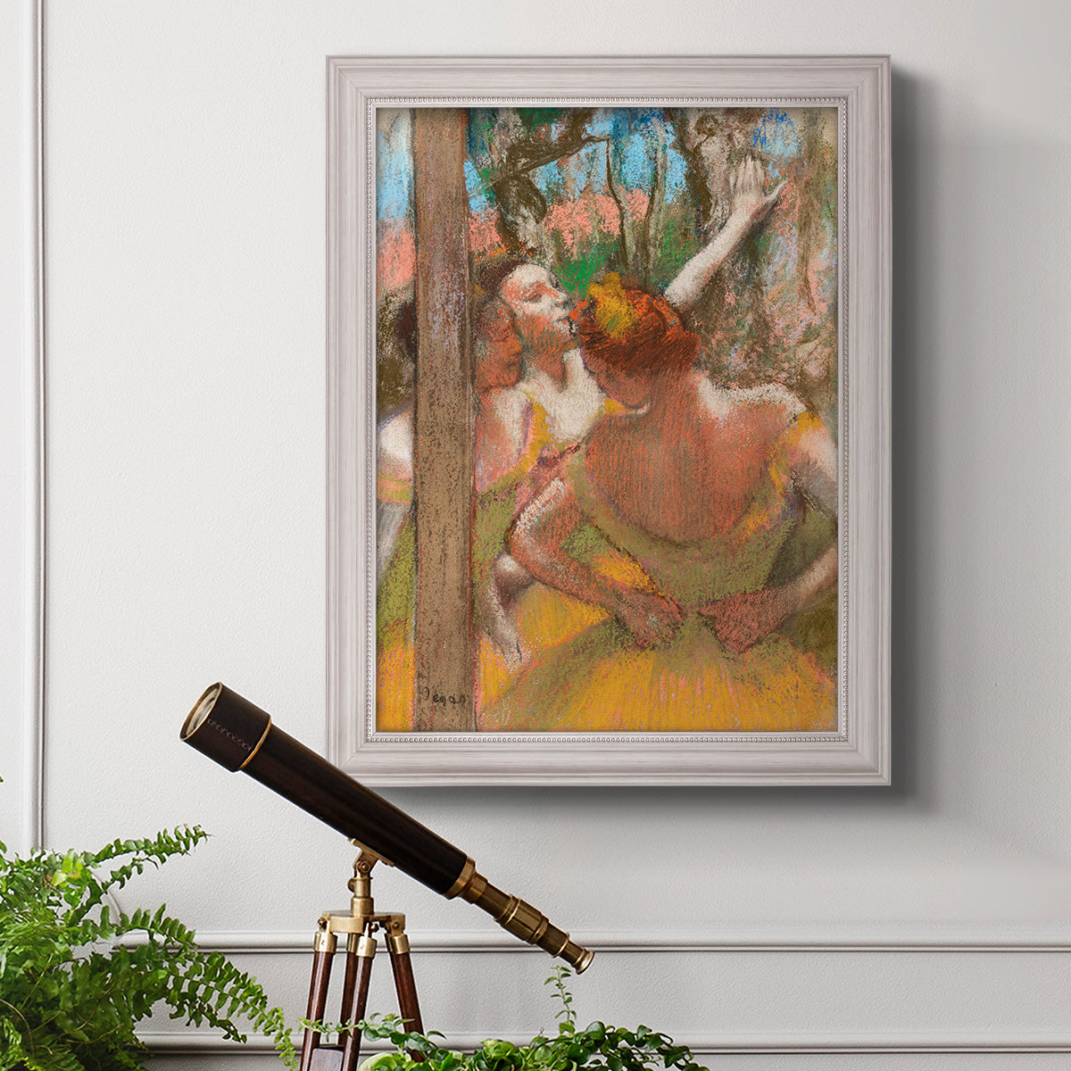 Impressionist ballet dancer composition by Edgar Degas in an ornate weathered white frame displayed in a light-toned interior setting.