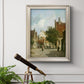 Rustic European street scene painting by Adriaan Eversen in an ornate champagne frame displayed in a light-toned interior setting.
