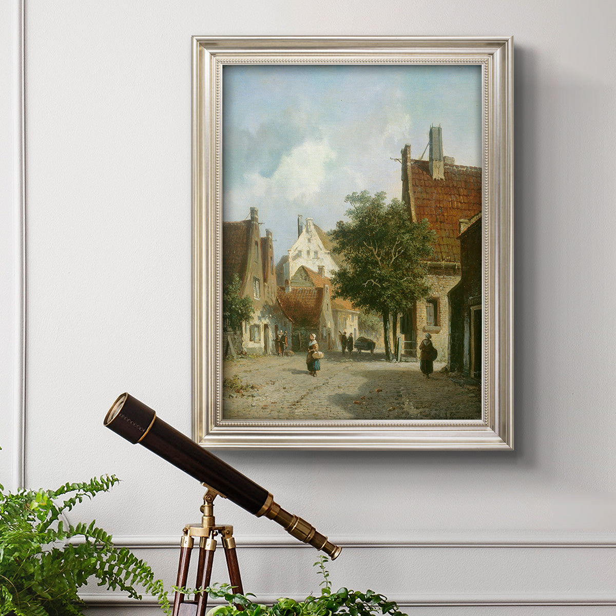 Rustic European street scene painting by Adriaan Eversen in an ornate champagne frame displayed in a light-toned interior setting.