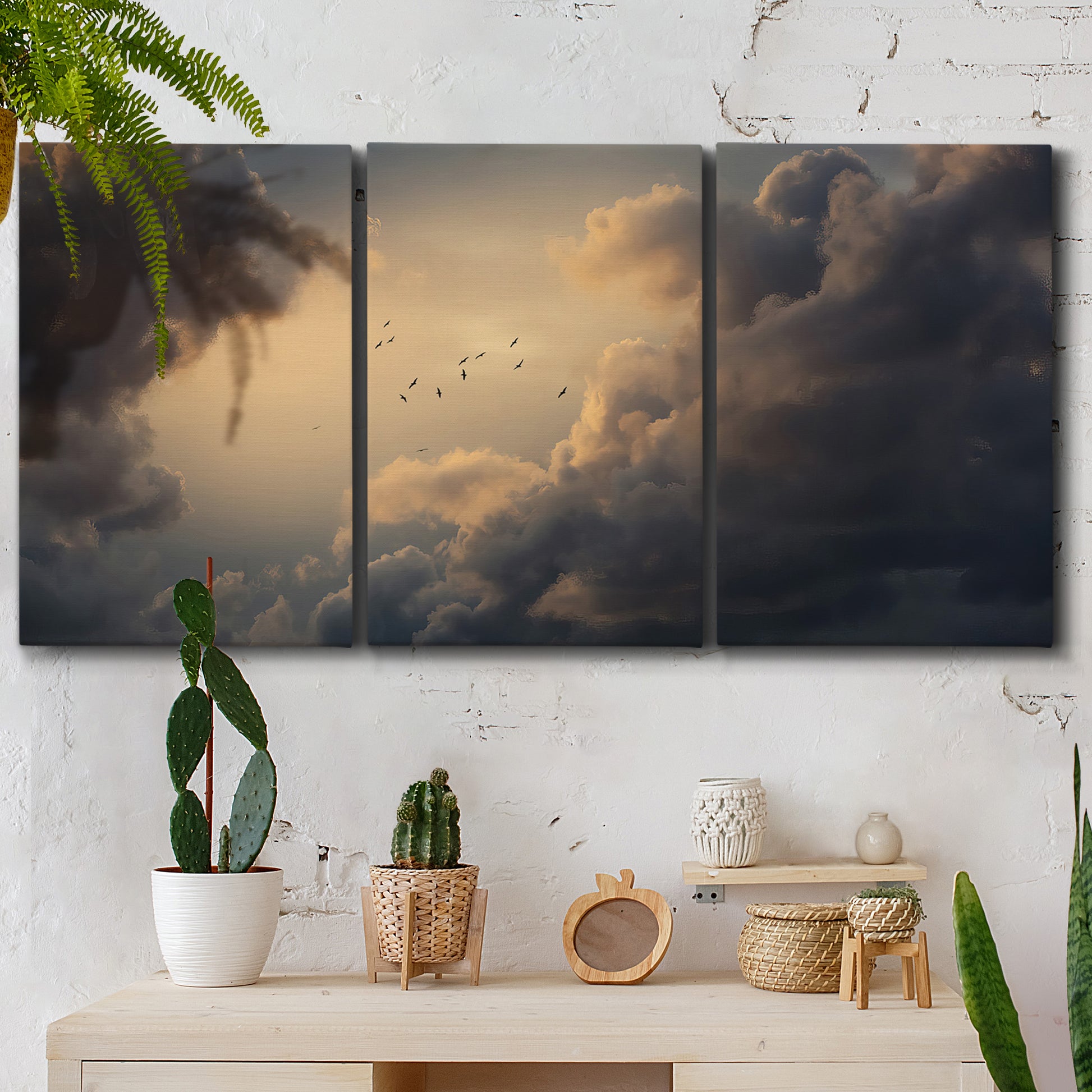 Three-panel canvas wall art featuring surreal floating figures above landscape, displayed in a boho-chic entryway above a console table.