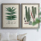 Set of two gray barnwood framed canvas prints depicting varied green fronds, roots, spores, and archival labels arranged across two complementary compositions above a sofa in a bright living space.