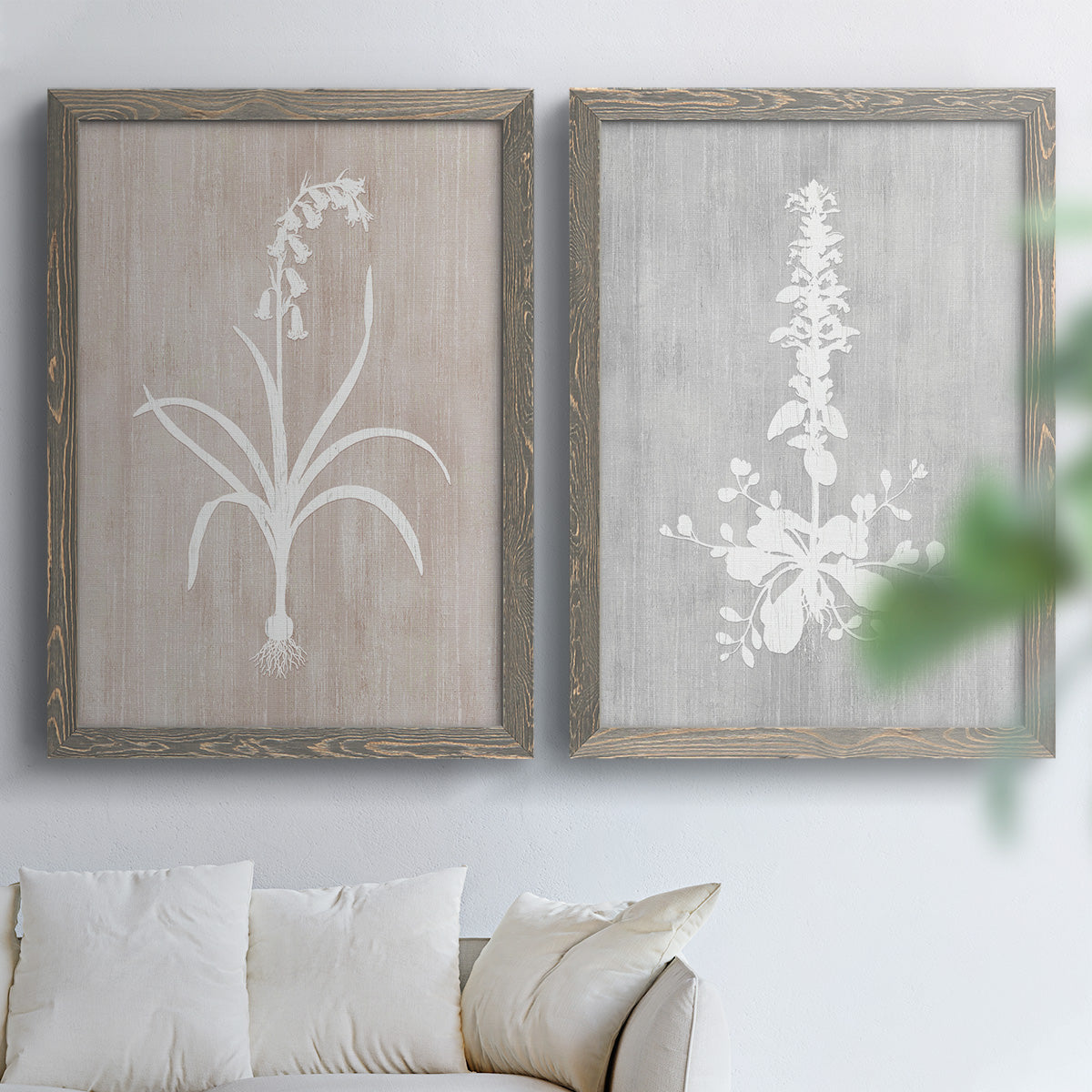 Set of two gray barnwood framed canvas prints depicting delicate stems, leaves, and blossoms against gray taupe and pale blue panels arranged across two complementary compositions above a sofa in a bright living space.