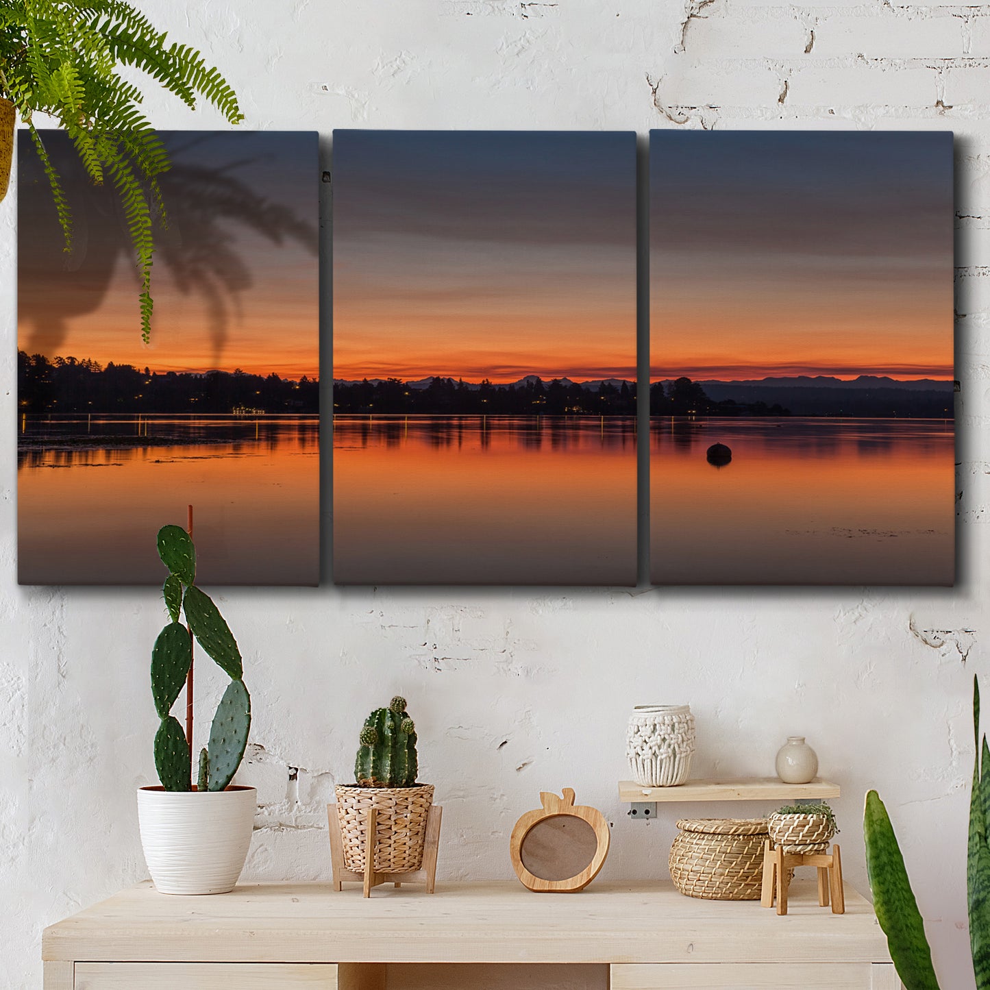 Three-panel canvas wall art featuring glowing sunset over water, displayed in a boho-chic entryway above a console table.