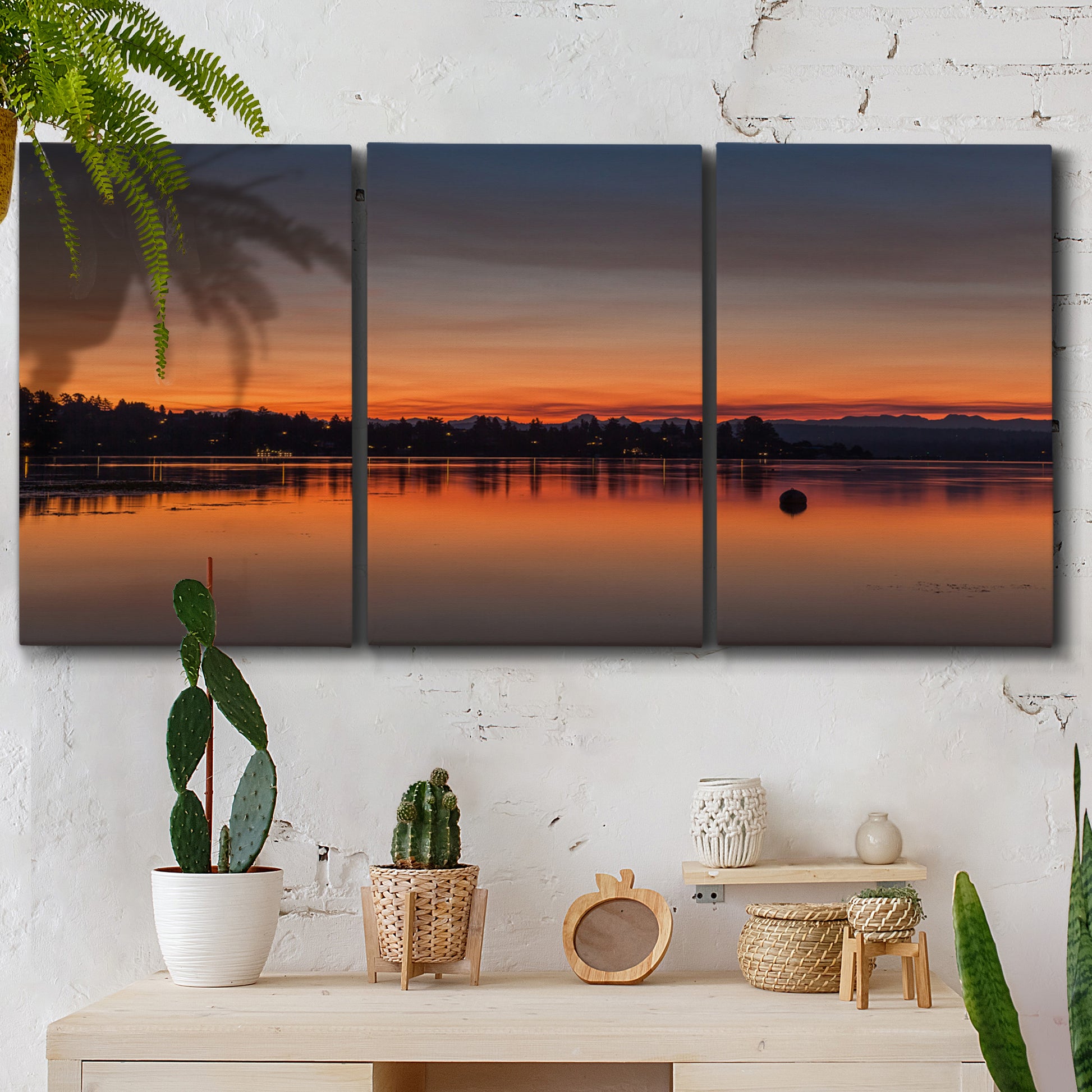 Three-panel canvas wall art featuring glowing sunset over water, displayed in a boho-chic entryway above a console table.