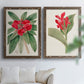 Set of two walnut barnwood framed canvas prints depicting large green leaves, red blossoms, and archival cream paper arranged across two complementary compositions above a sofa in a bright living space.
