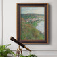 Impressionist landscape view of Vétheuil by Claude Monet in an ornate bronzed mahogany wood frame displayed in a light-toned interior setting.