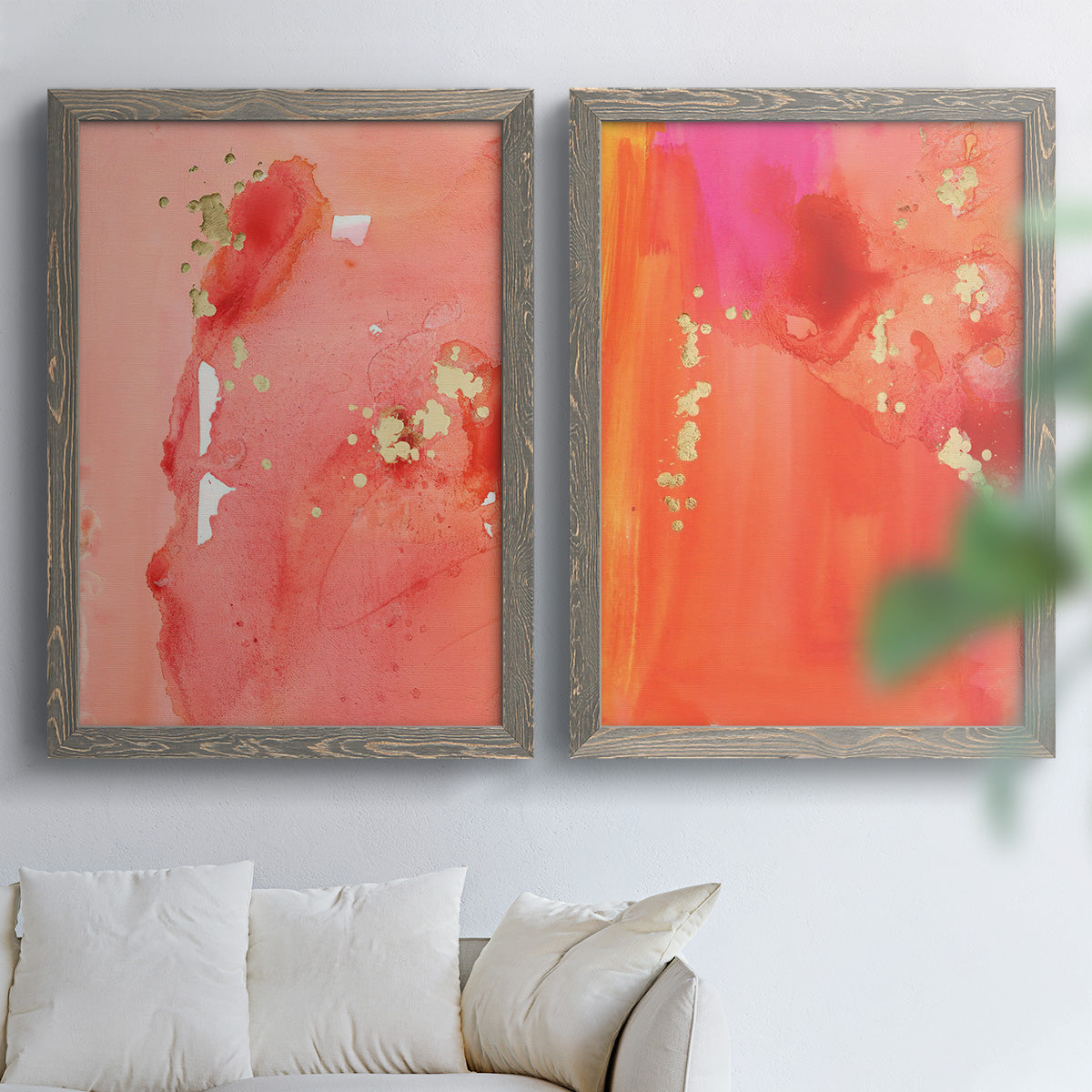 Set of two gray barnwood framed canvas prints depicting translucent warm washes, drips, and scattered metallic accents arranged across two complementary compositions above a sofa in a bright living space.