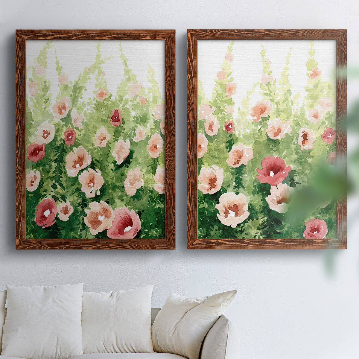 Set of two maple barnwood framed canvas prints depicting loose blossoms, green stems, and sunlit watercolor texture arranged across two complementary compositions above a sofa in a bright living space.