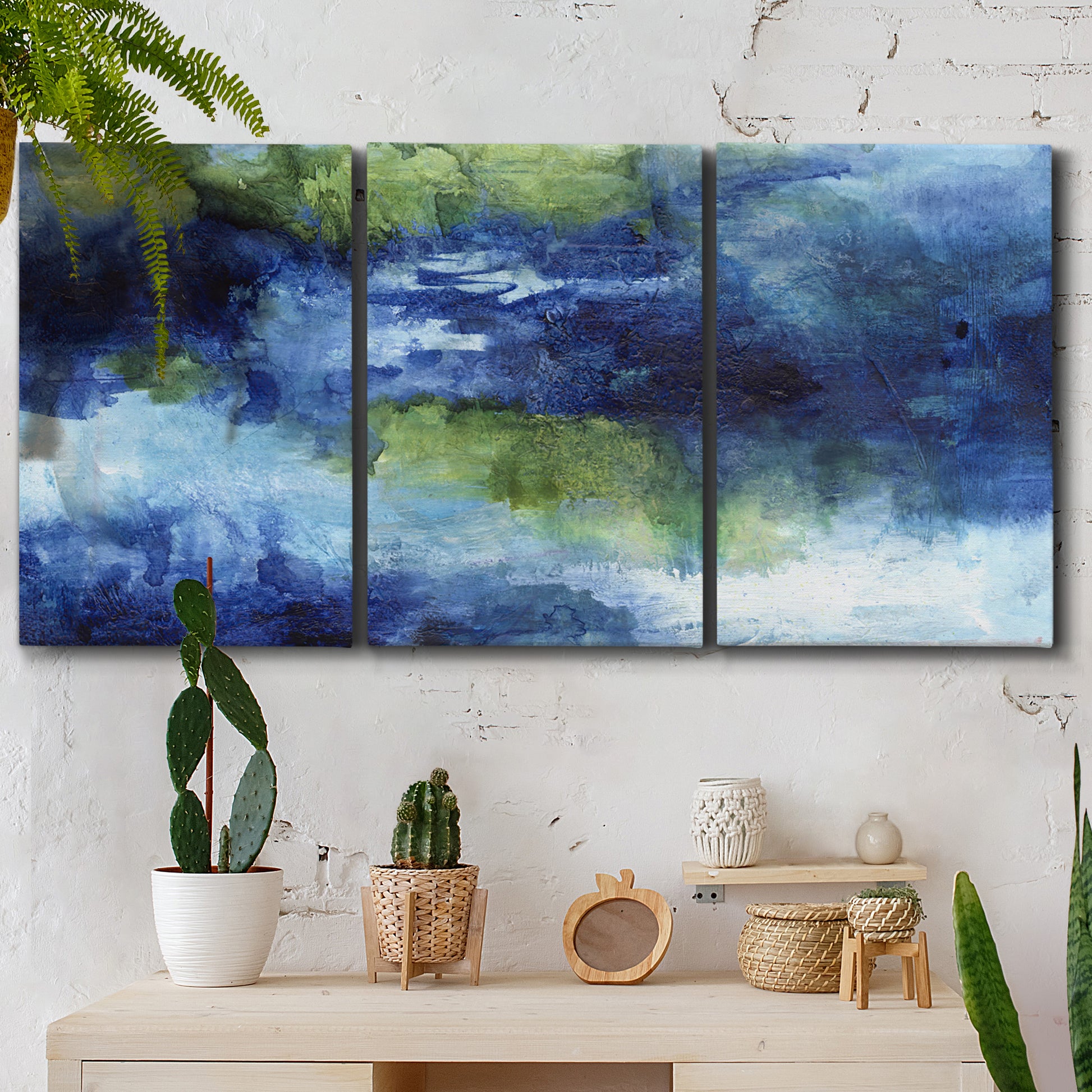 Three-panel canvas wall art featuring flowing blue abstract watercolor, displayed in a boho-chic entryway above a console table.