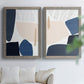 Set of two gray barnwood framed canvas prints depicting rounded dark forms, pale sand fields, and clean modern edges arranged across two complementary compositions above a sofa in a bright living space.
