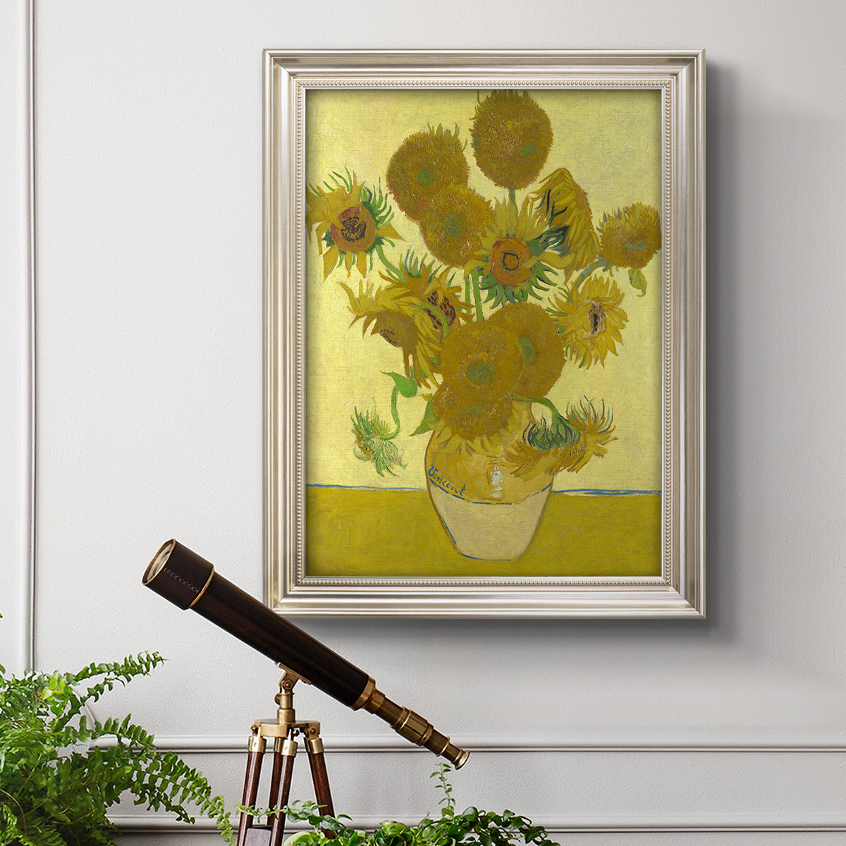 Impressionist sunflower still life painting by Vincent van Gogh in an ornate champagne frame displayed in a light-toned interior setting.