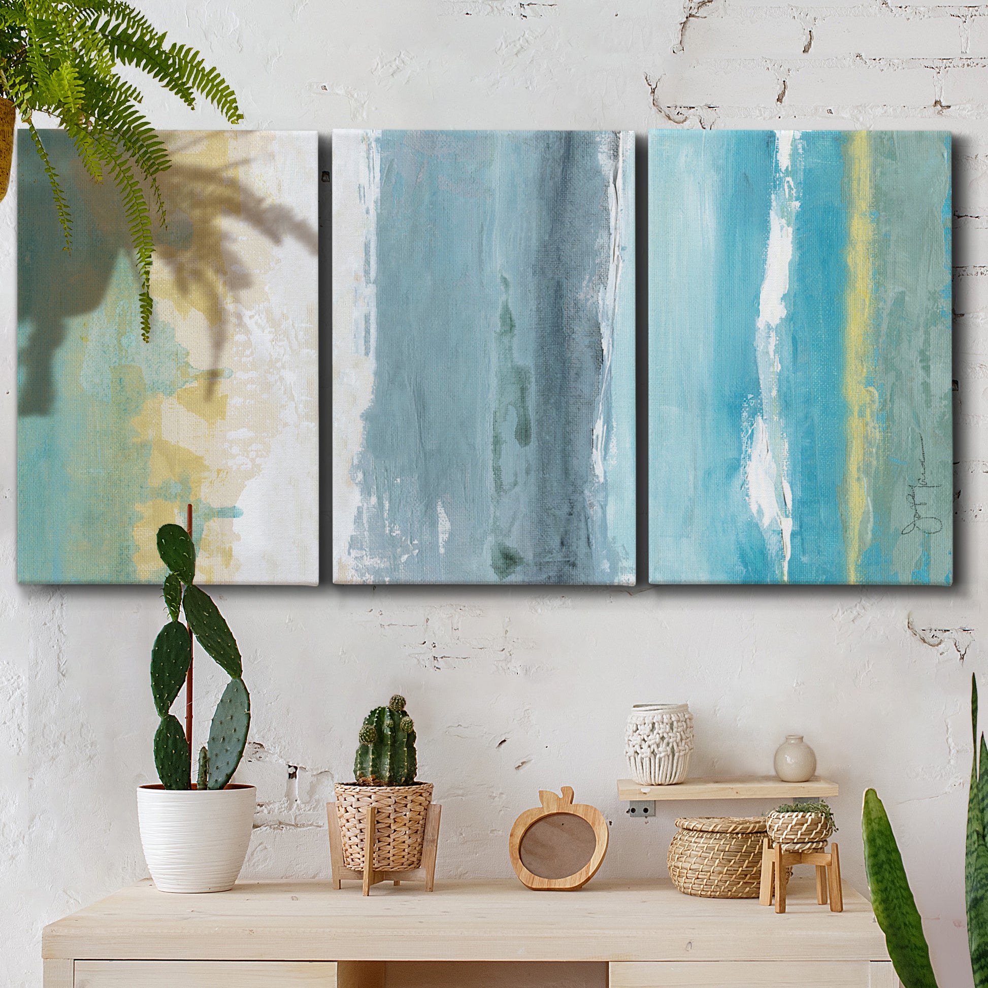 Three-panel canvas wall art featuring abstract coastal beach textures, displayed in a boho-chic entryway above a console table.