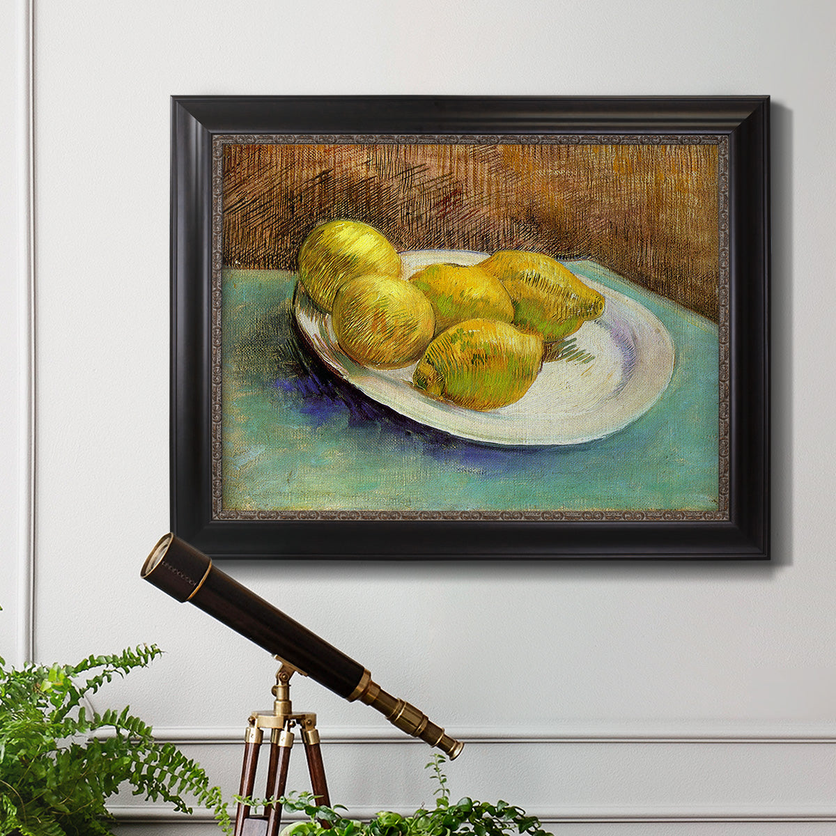 Impressionist still life with lemons by Vincent van Gogh in an ornate black frame with gilded inner detail displayed in a light-toned interior setting.