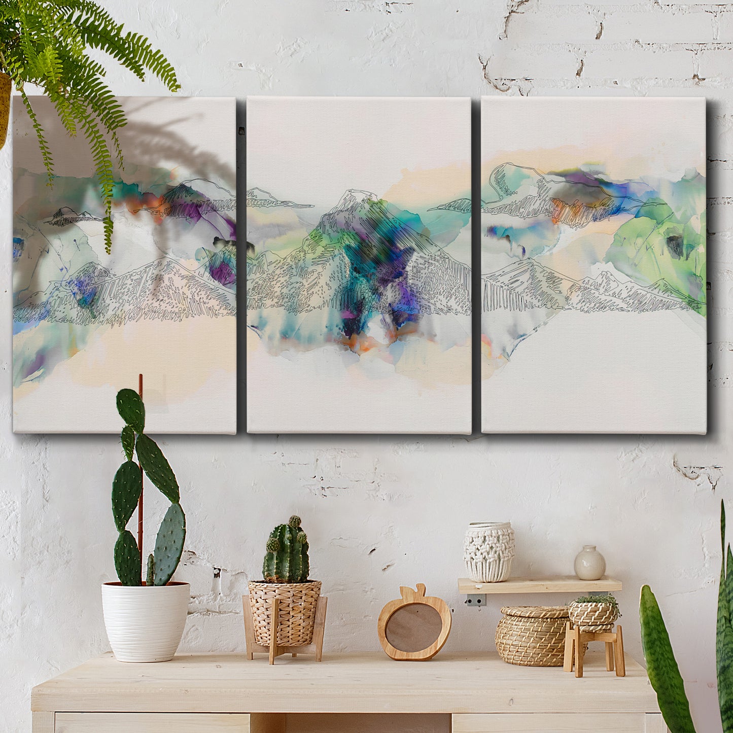 Three-panel canvas wall art featuring abstract mountain range watercolor, displayed in a boho-chic entryway above a console table.