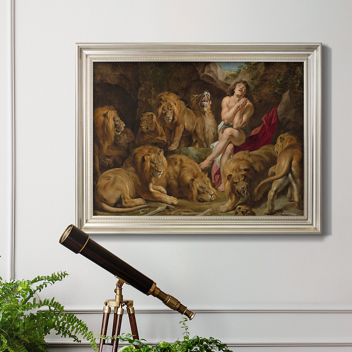 Dramatic biblical painting of Daniel with lions by Peter Paul Rubens in an ornate champagne frame displayed in a light-toned interior setting.