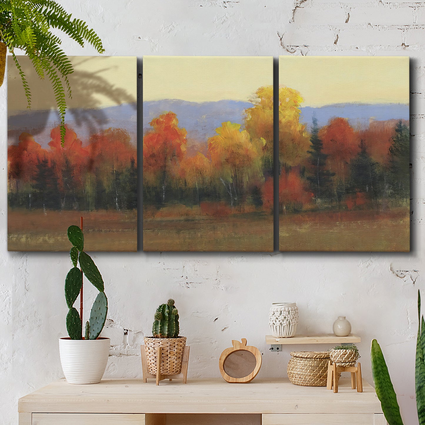 Three-panel canvas wall art featuring autumn landscape changing foliage, displayed in a boho-chic entryway above a console table.