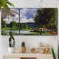 Three-panel canvas wall art featuring riverbank landscape near village, displayed in a boho-chic entryway above a console table.