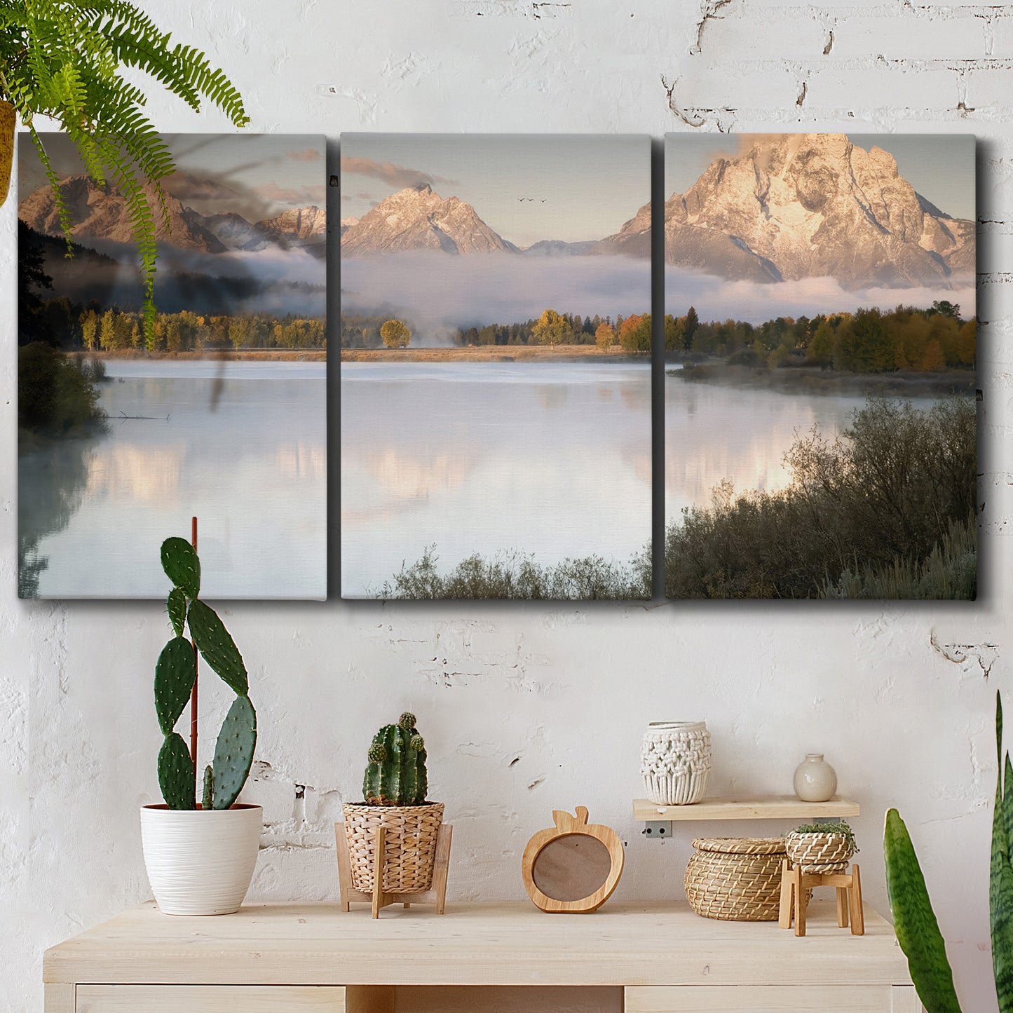 Three-panel canvas wall art featuring fog drifting over winding river, displayed in a boho-chic entryway above a console table.