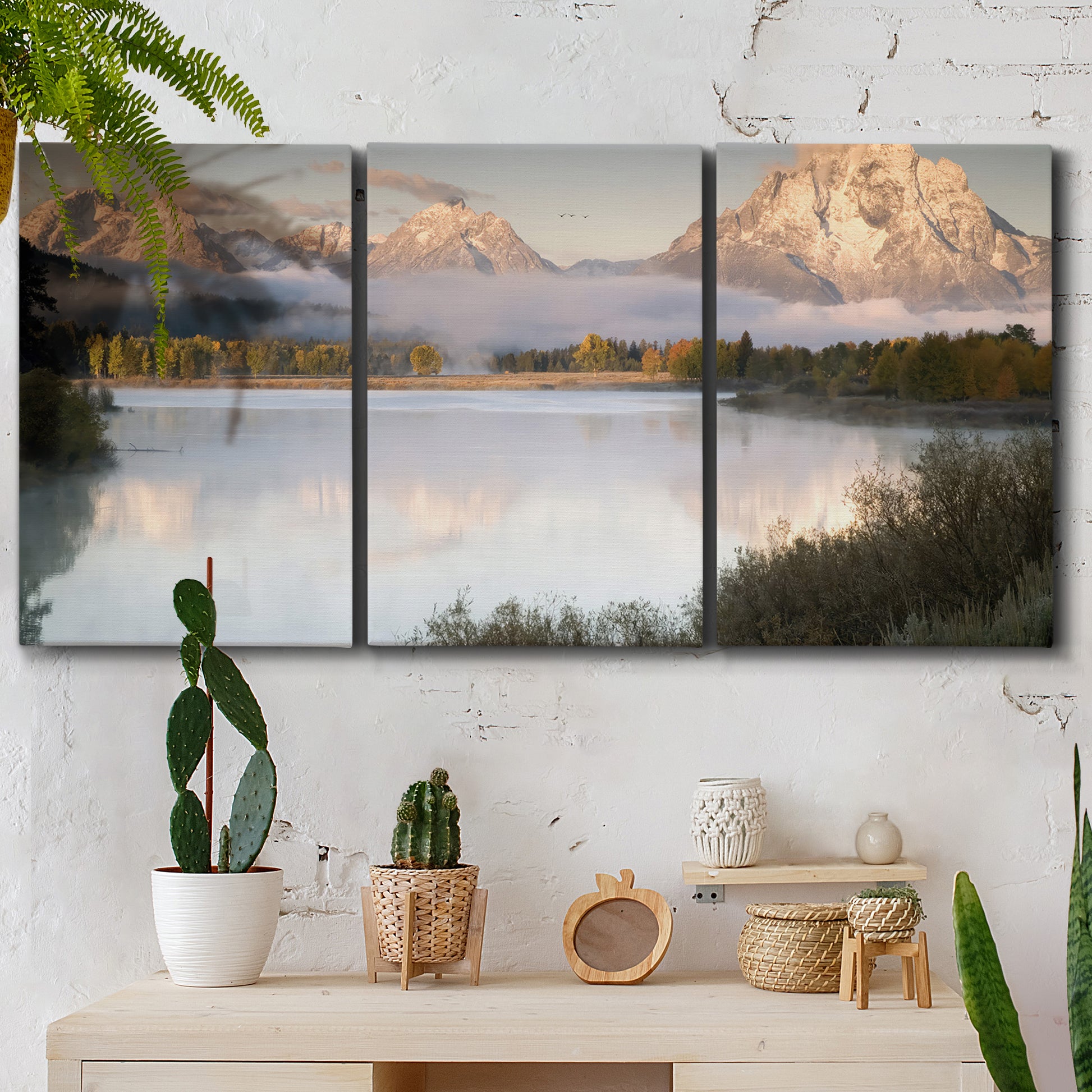 Three-panel canvas wall art featuring fog drifting over winding river, displayed in a boho-chic entryway above a console table.
