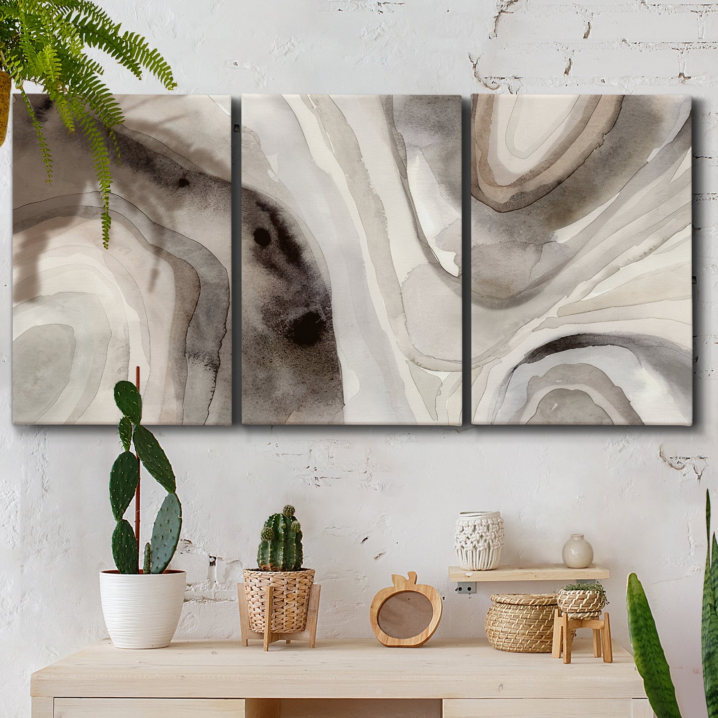 Three-panel canvas wall art featuring layered stone inspired abstract forms, displayed in a boho-chic entryway above a console table.