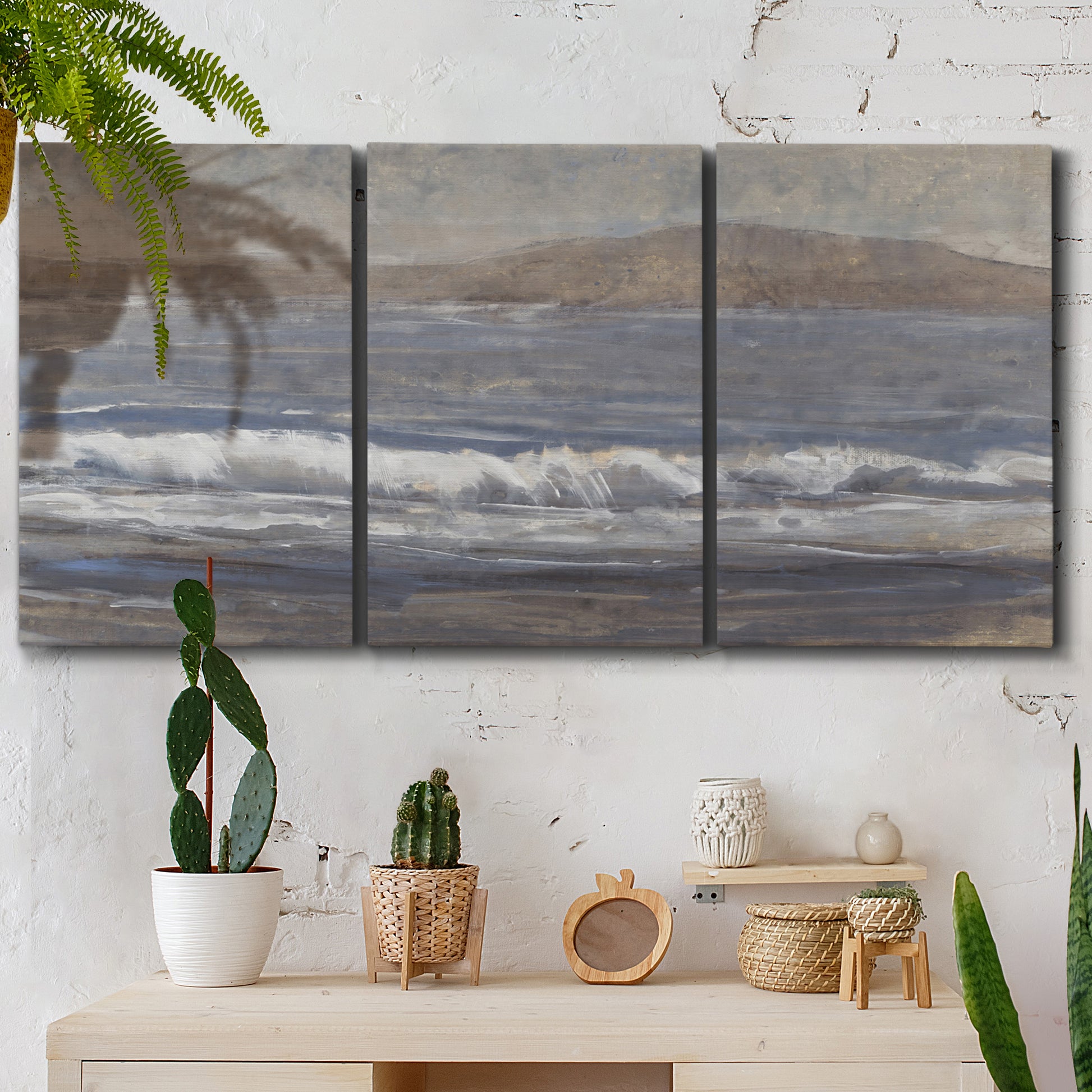 Three-panel canvas wall art featuring shoreline between land and sea, displayed in a boho-chic entryway above a console table.