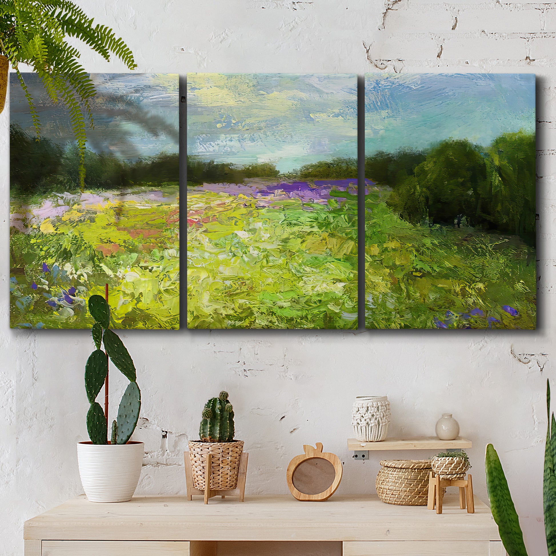 Three-panel canvas wall art featuring pastoral field with wildflowers, displayed in a boho-chic entryway above a console table.