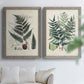 Set of two gray barnwood framed canvas prints depicting varied green fronds, roots, spores, and archival labels arranged across two complementary compositions above a sofa in a bright living space.