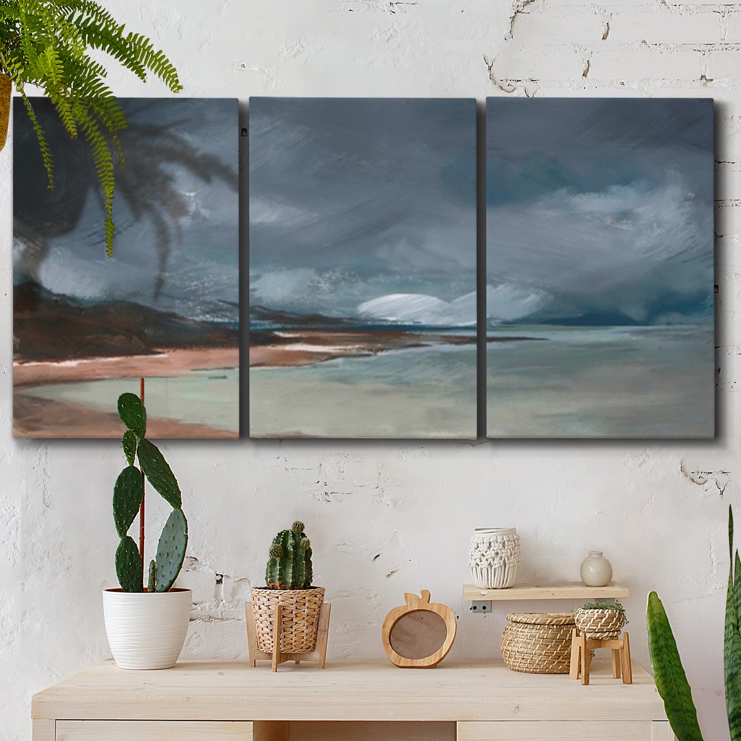 Three-panel canvas wall art featuring stormy sea glass toned coastline, displayed in a boho-chic entryway above a console table.