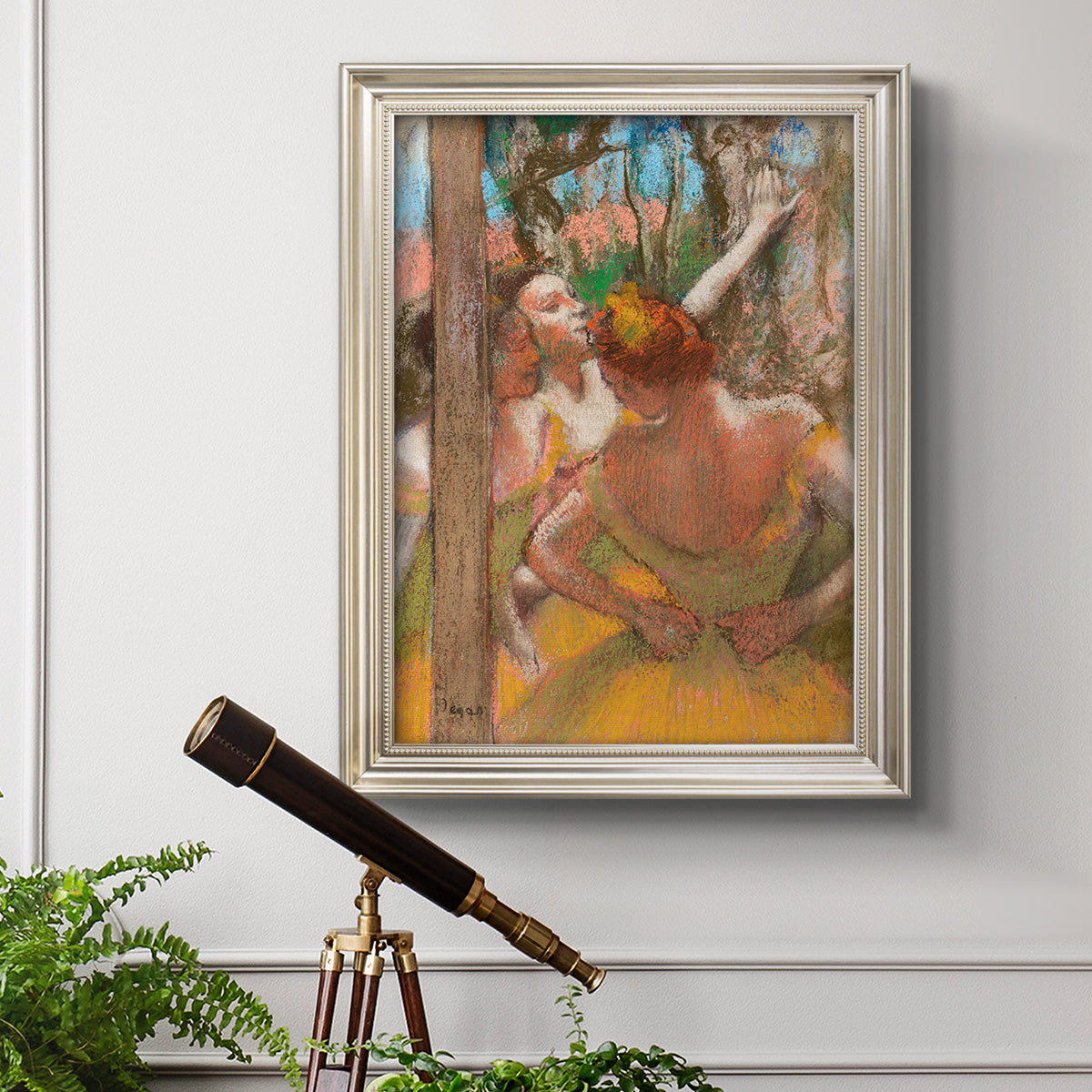 Impressionist ballet dancer composition by Edgar Degas in an ornate champagne frame displayed in a light-toned interior setting.