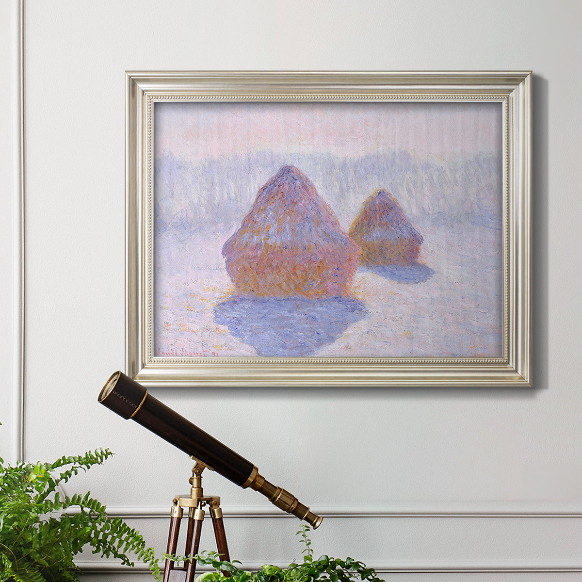 Impressionist winter haystack scene with sunlight by Claude Monet in an ornate champagne frame displayed in a light-toned interior setting.