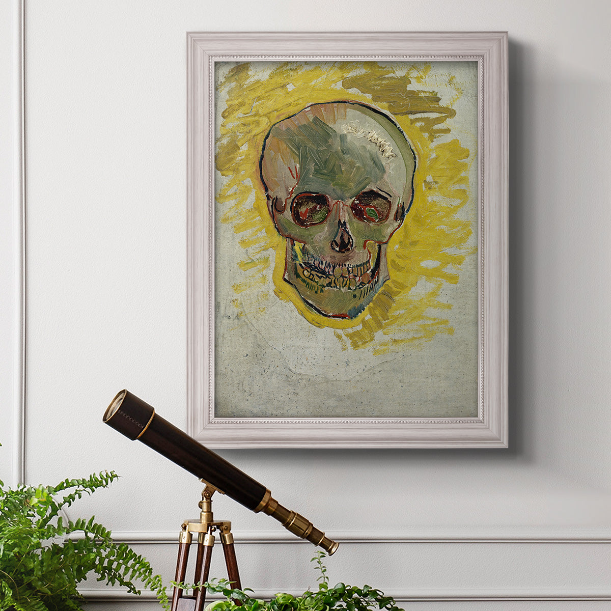 Expressive skull study painting by Vincent van Gogh in an ornate weathered white frame displayed in a light-toned interior setting.