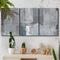 Three-panel canvas wall art featuring cool toned industrial abstract blues, displayed in a boho-chic entryway above a console table.