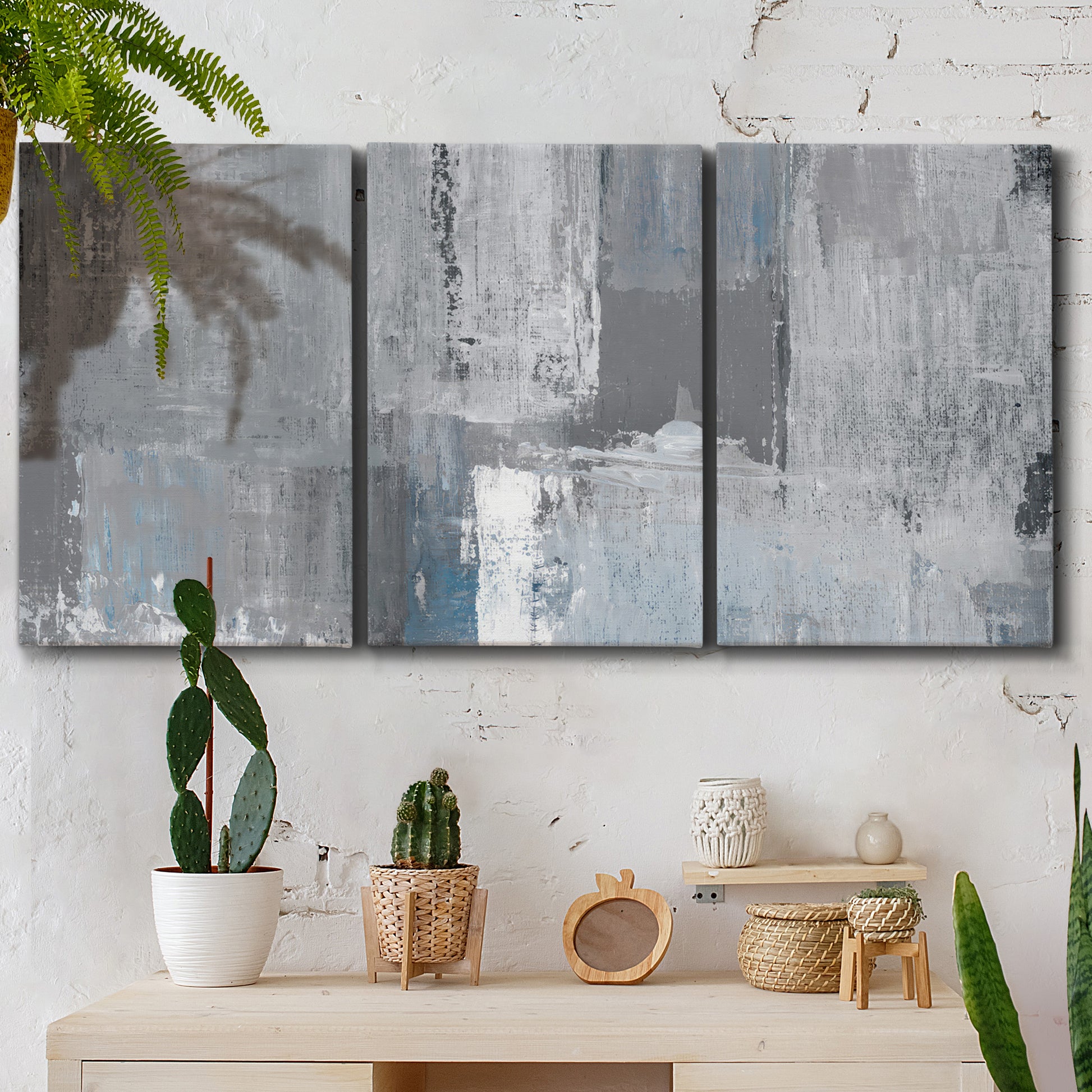 Three-panel canvas wall art featuring cool toned industrial abstract blues, displayed in a boho-chic entryway above a console table.