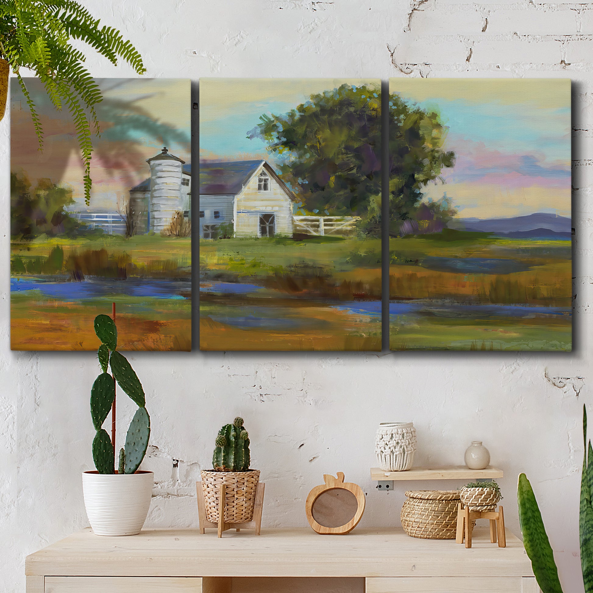 Three-panel canvas wall art featuring rural barn landscape with fields, displayed in a boho-chic entryway above a console table.