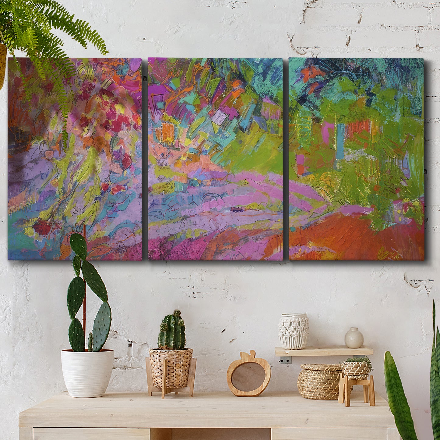 Three-panel canvas wall art featuring vibrant abstract with dramatic motion, displayed in a boho-chic entryway above a console table.