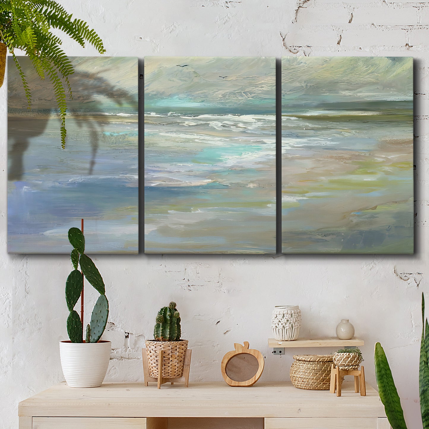 Three-panel canvas wall art featuring soft coastal beach light landscape, displayed in a boho-chic entryway above a console table.