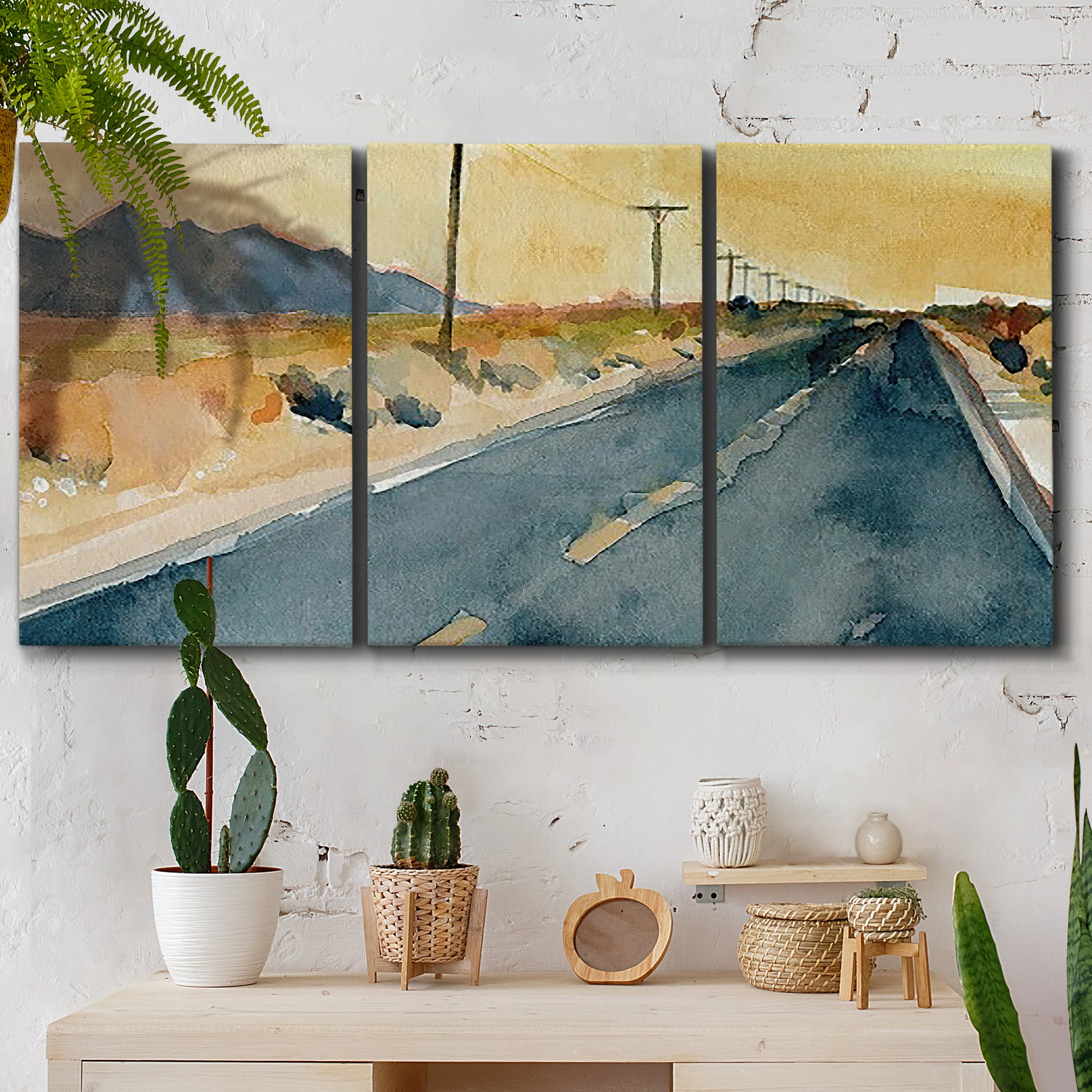 Three-panel canvas wall art featuring empty highway stretching through landscape, displayed in a boho-chic entryway above a console table.